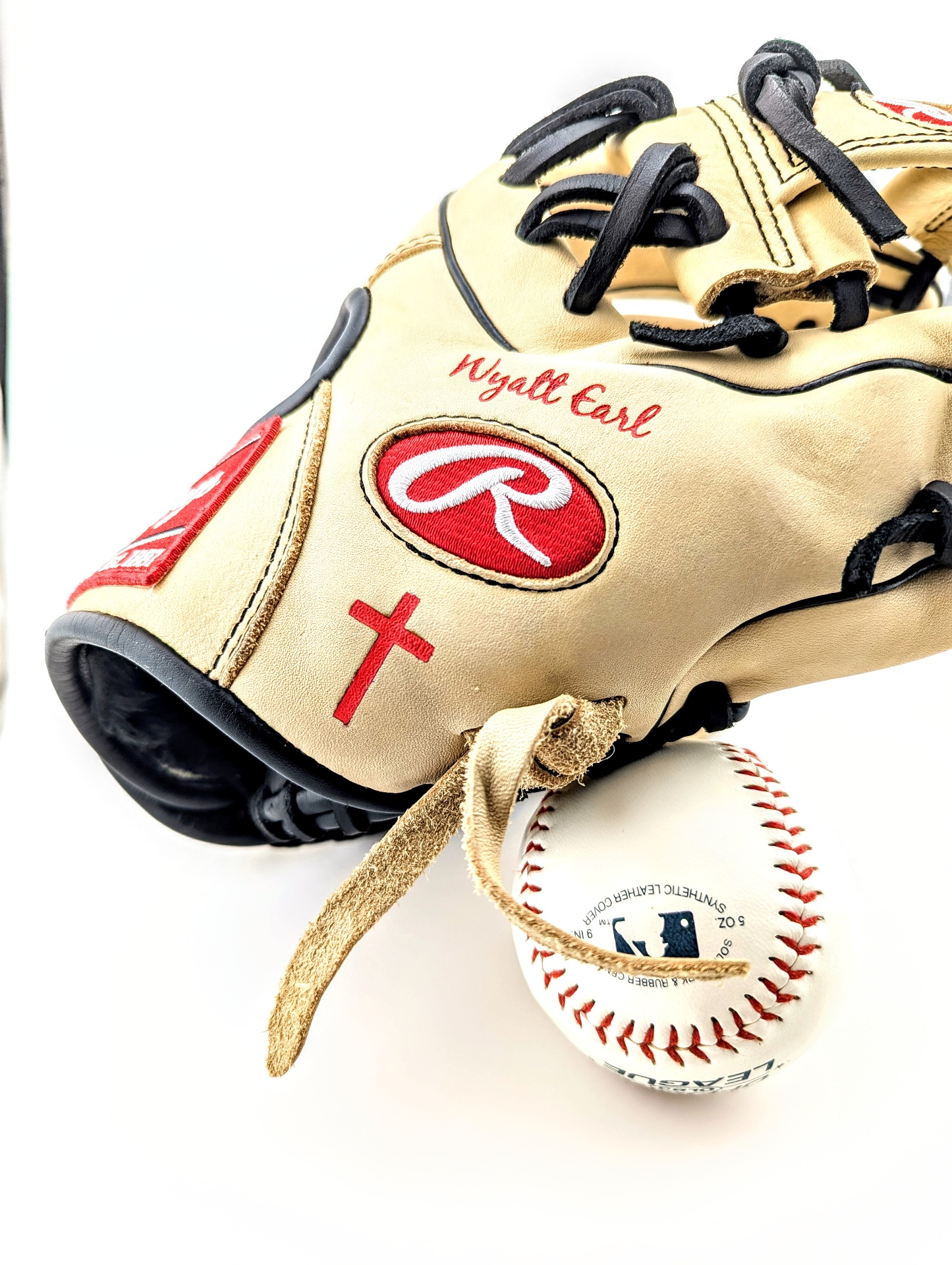 Red script name engraved on tan Rawlings baseball glove with small cross detail
